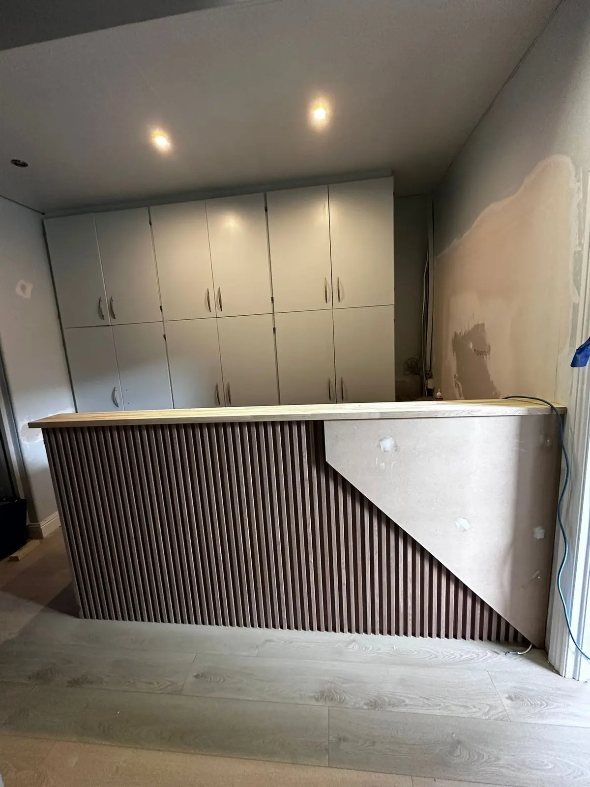 Slatted reception desk installed, storage behind