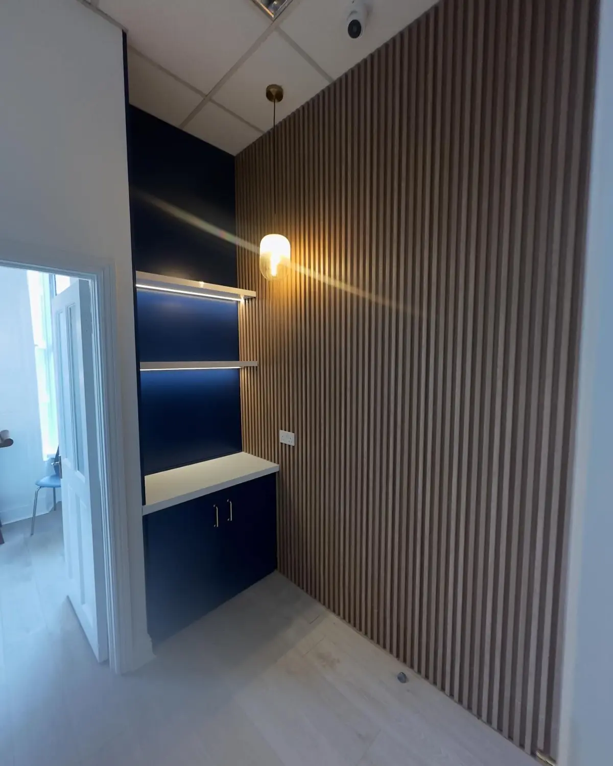 Slatted wall and blue cabinetry with lighting