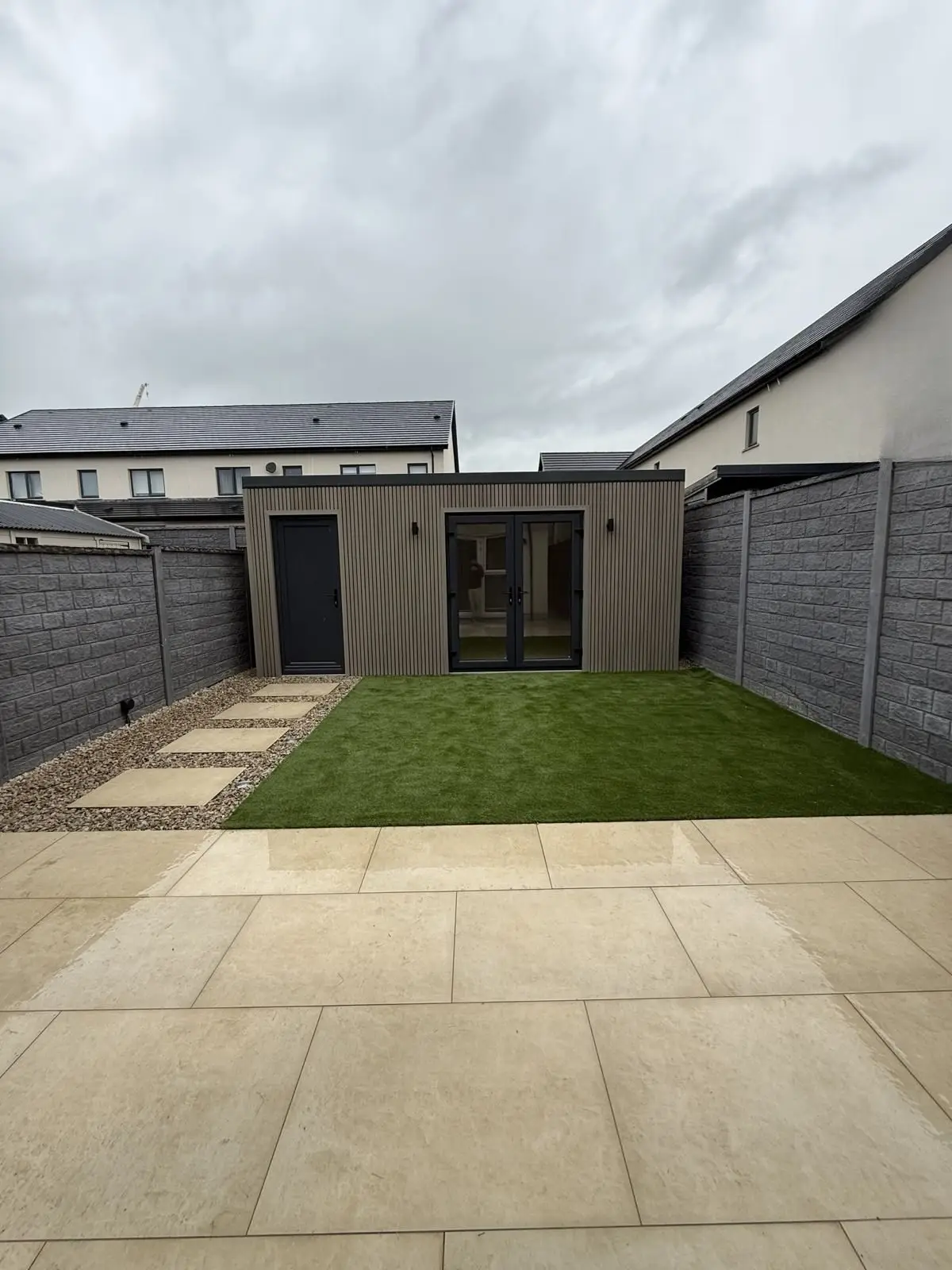 Clad garden room with store, stepping stones and patio
