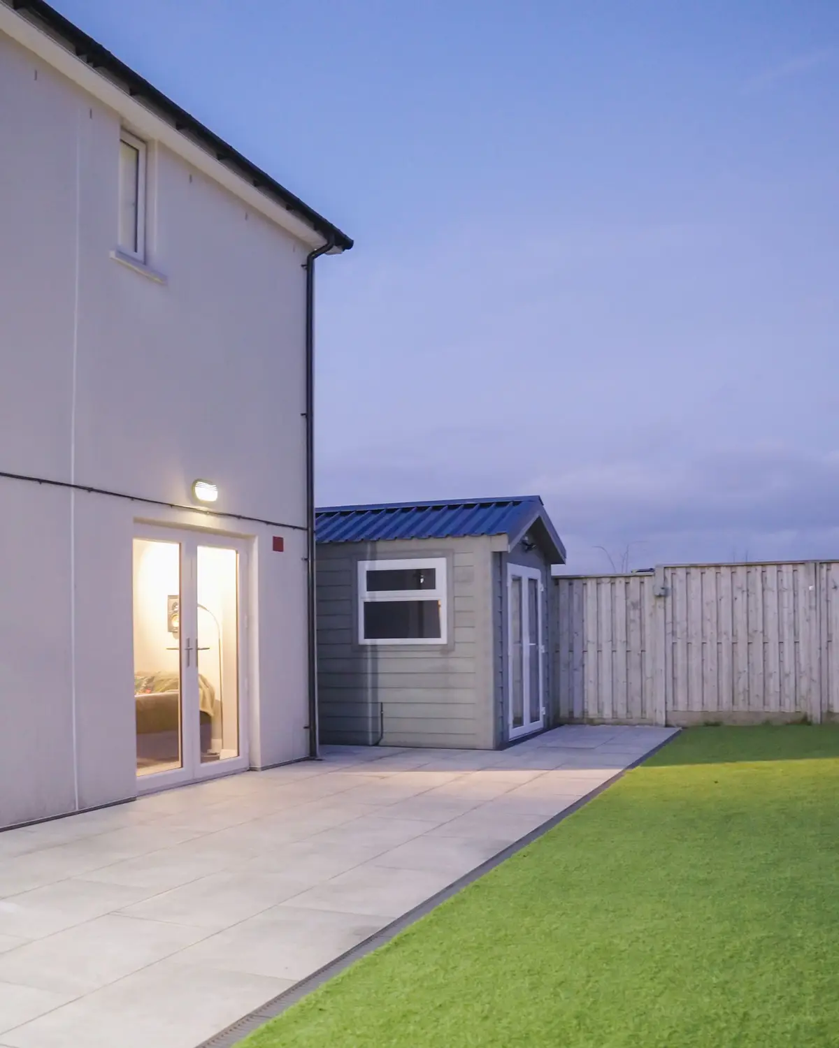Rear patio, lawn and garden store at dusk