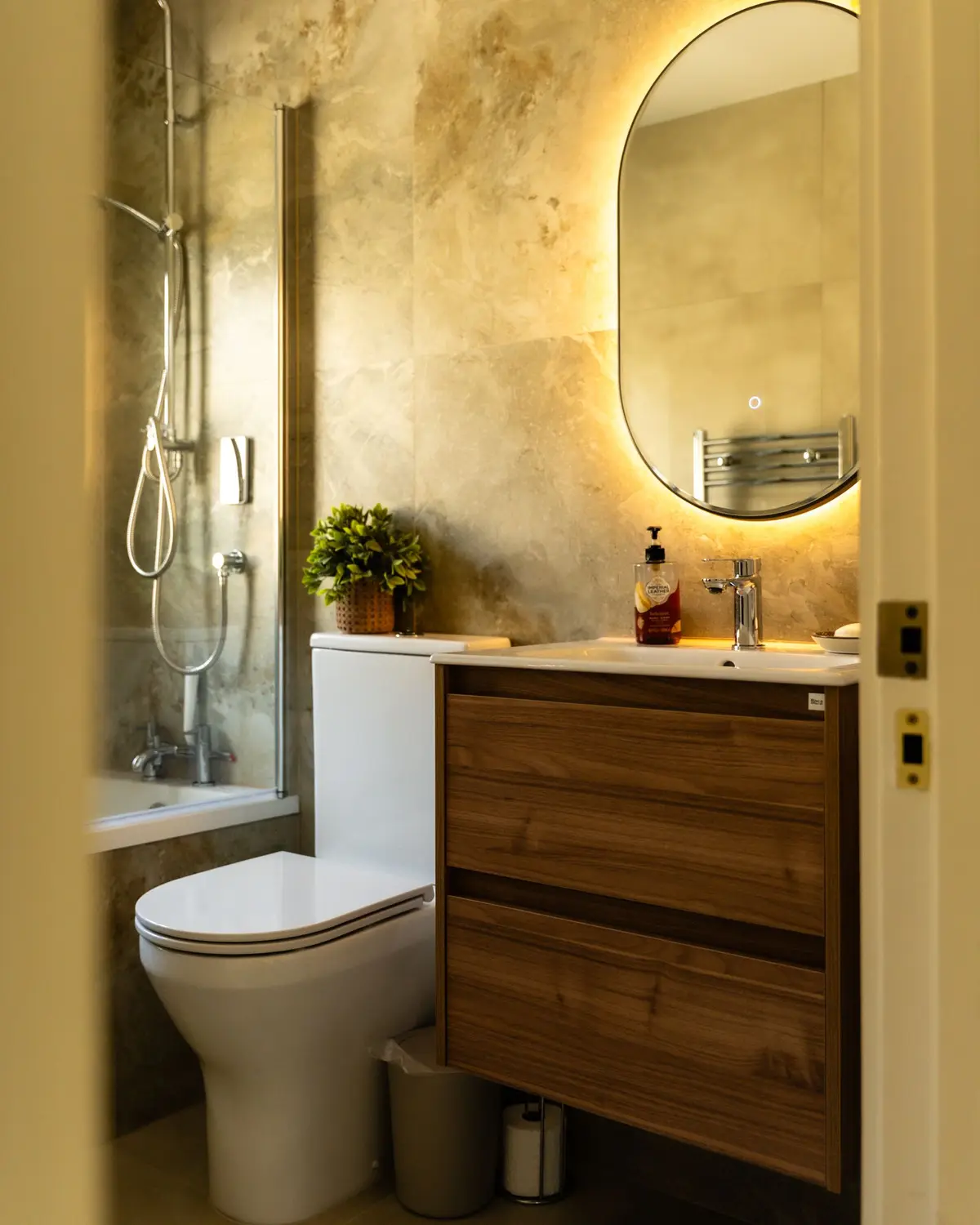 En suite: stone-look tile, lit oval mirror