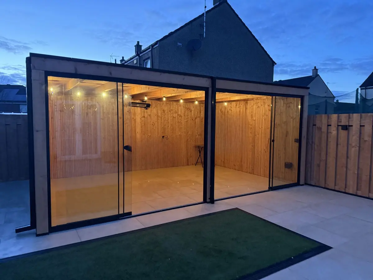 Glass-fronted garden room at dusk, porcelain patio