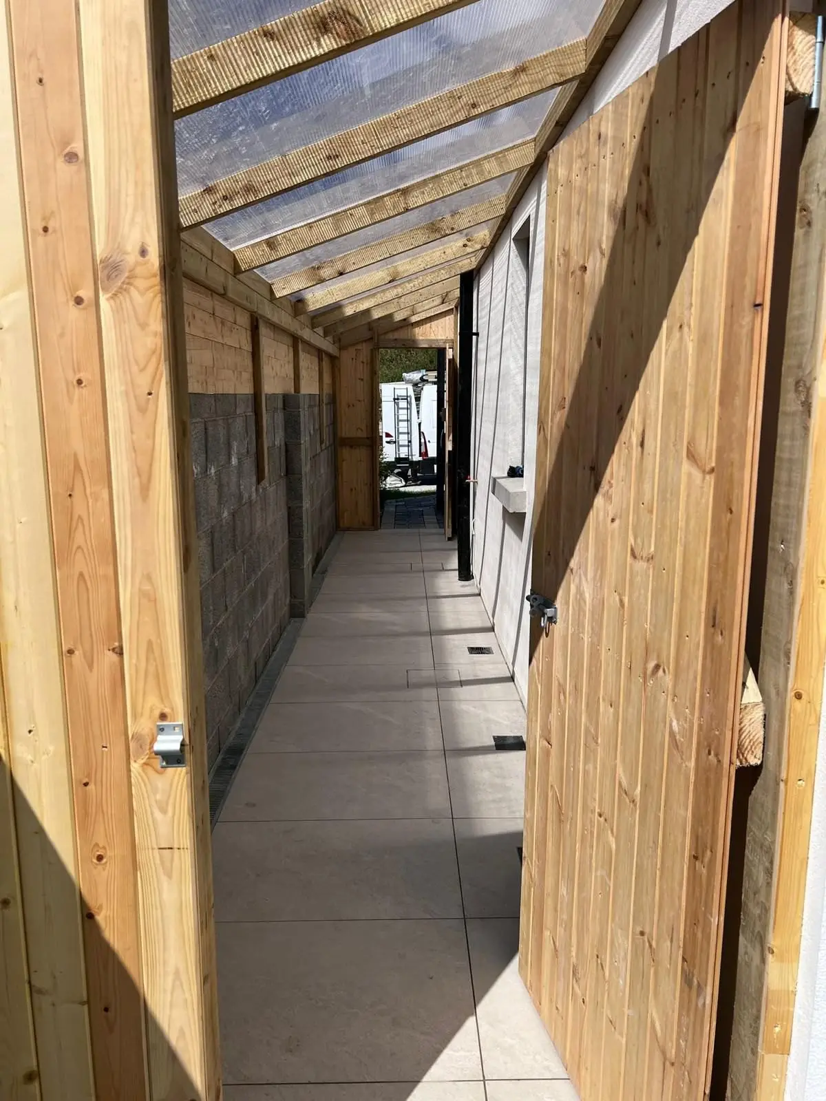 Timber lean-to cover with a clear roof over a porcelain side passage