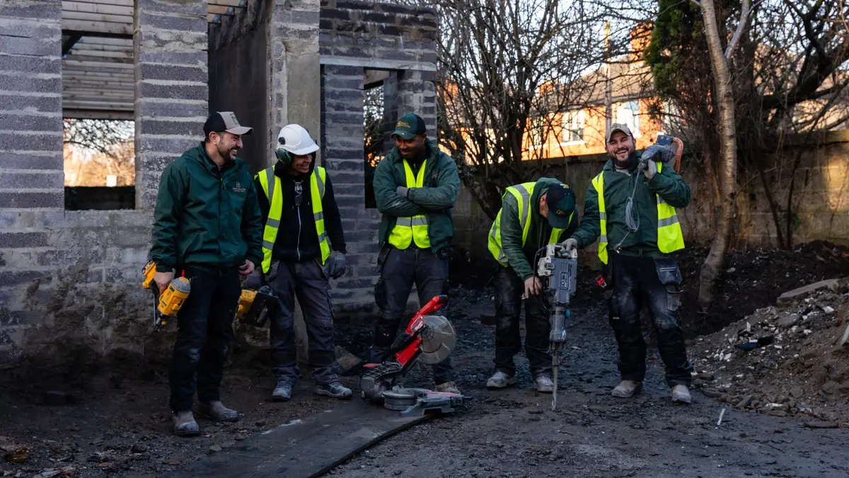 Crew on a live structural site, block shell behind