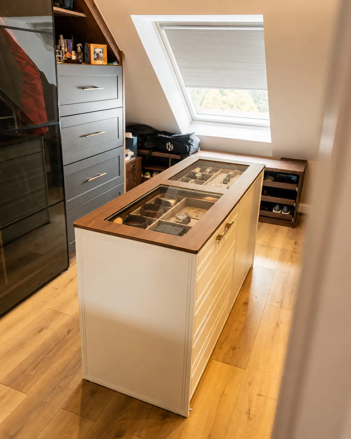 Attic dressing room with a central island, glass-topped display drawers holding watches, belts and jewellery, fitted drawers and eaves wardrobes under a rooflight, Rathcoole